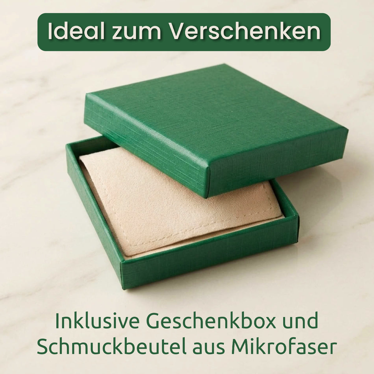 A green gift box with its lid partially open, showing a beige microfiber jewelry pouch inside. German text at the top reads 'Ideal zum Verschenken' and text at the bottom reads 'Inklusive Geschenkbox und Schmuckbeutel aus Mikrofaser'.