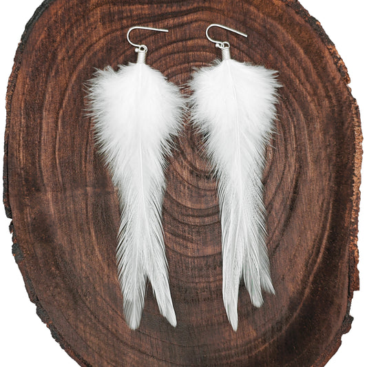 White feather earrings on a wooden surface. Boho hippie jewelry