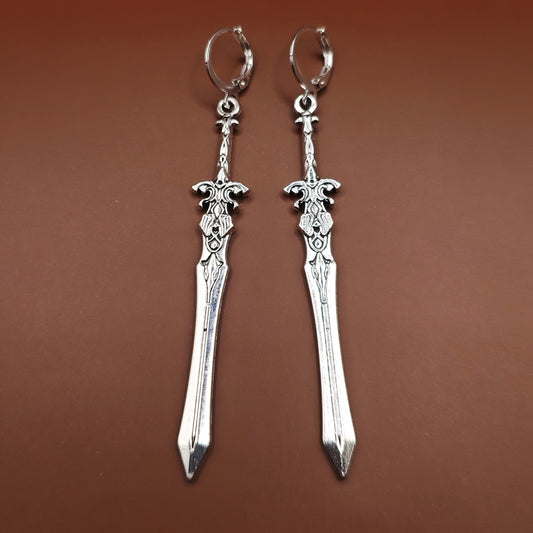 Medieval-style silver sword earrings with stainless steel huggie lever back hoops, perfect for fantasy fashion and cosplay.