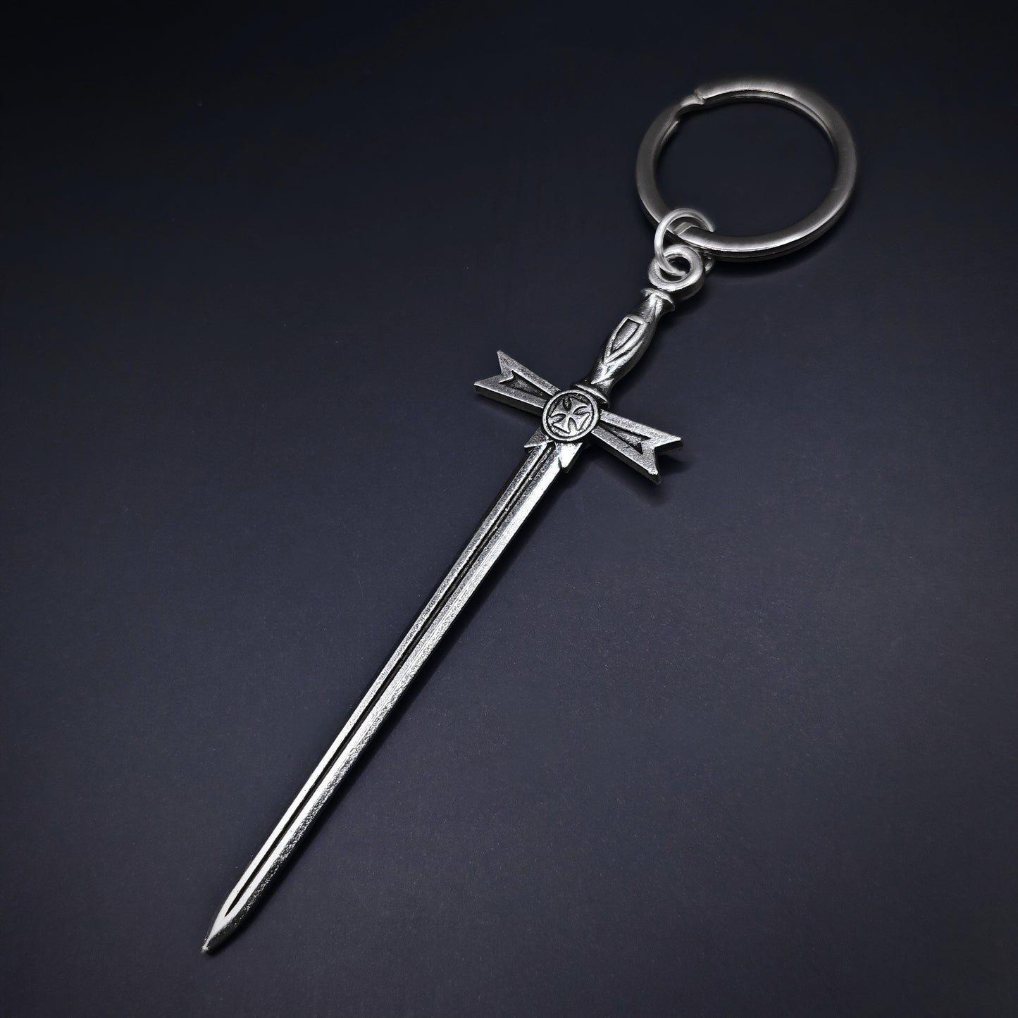 Silver keychain with a medieval sword design on a dark background
