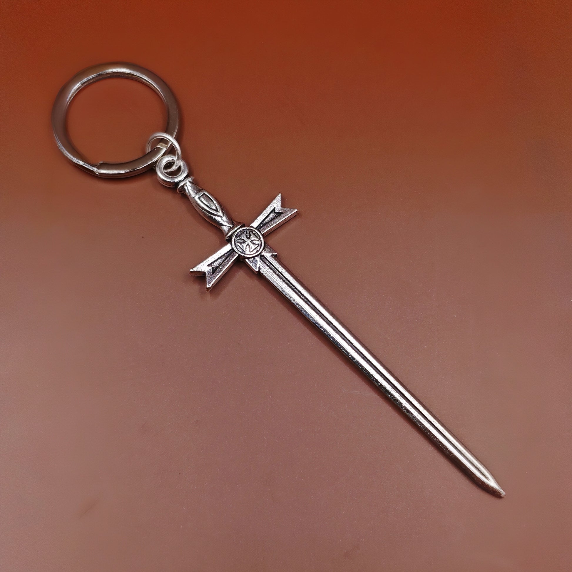 Silver keyring with cross and sword design on a brown background