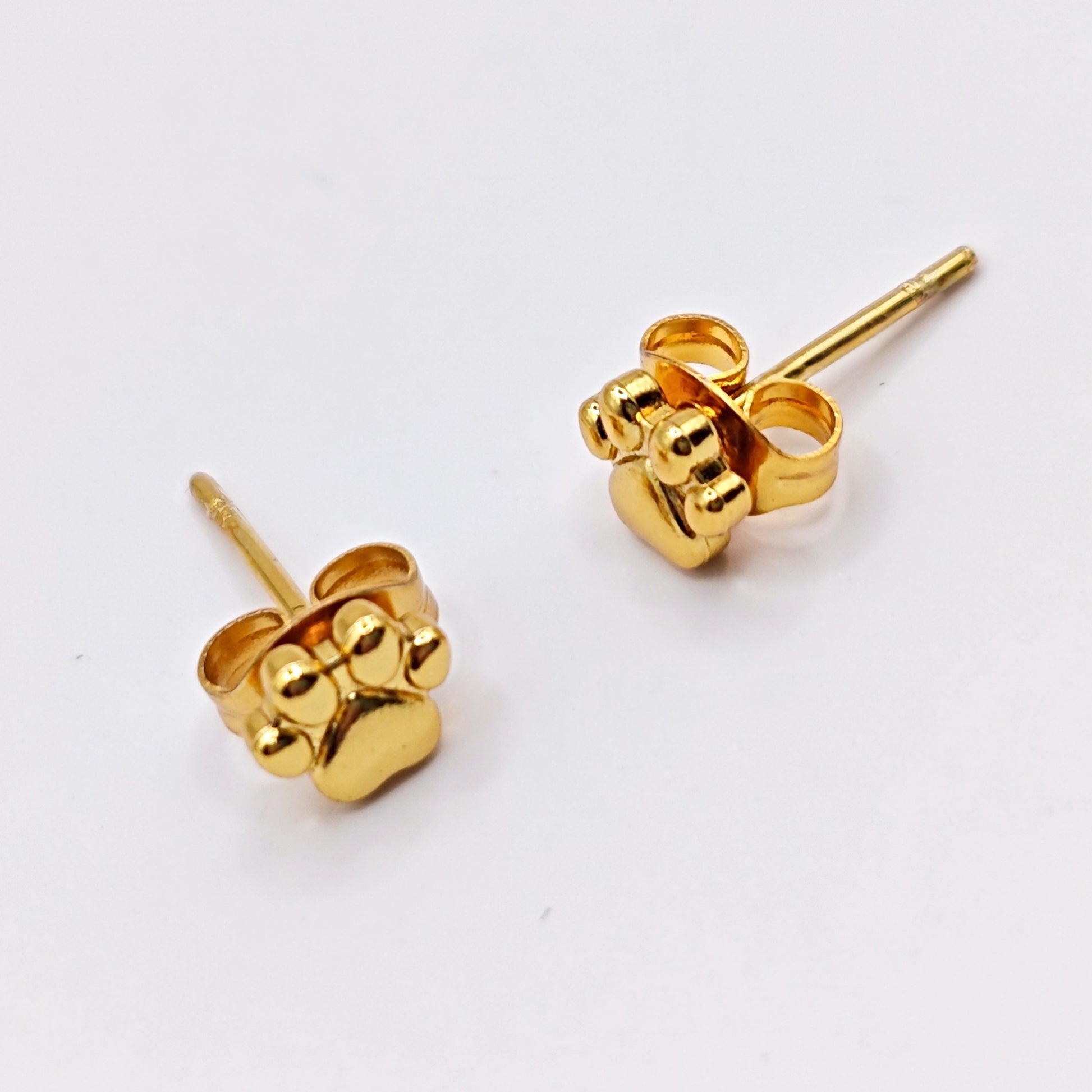 Gold dog paw print shaped earrings on a white background, made from stainless steel.