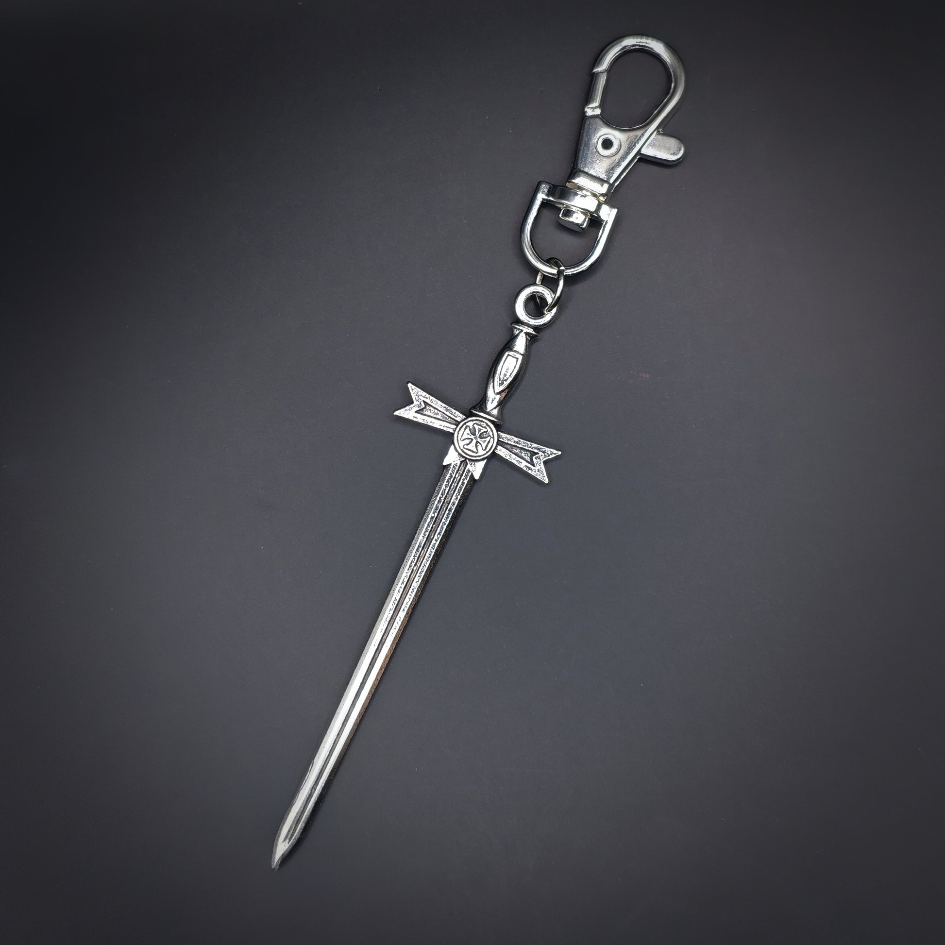 Silver sword-shaped keychain on a dark gray background