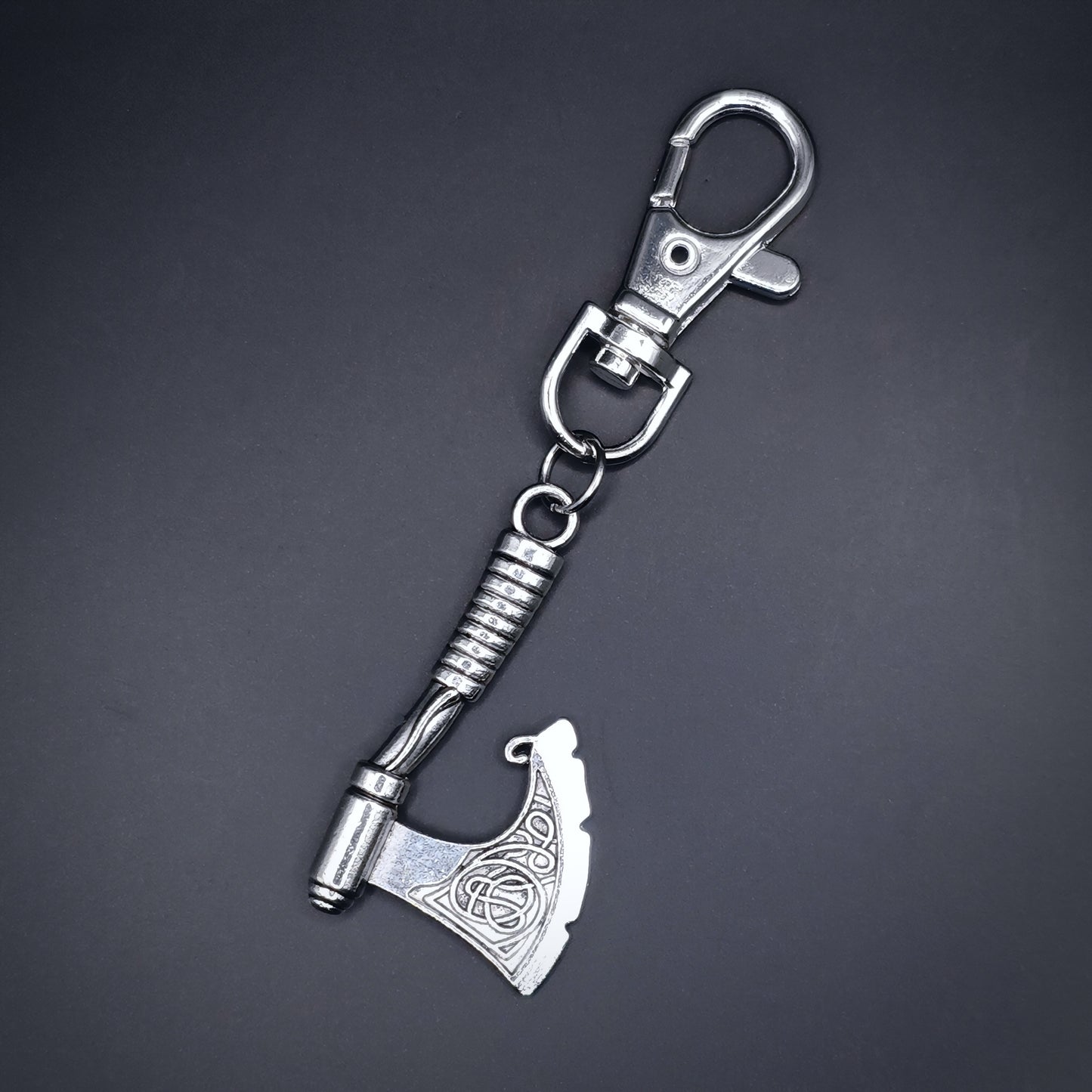 Silver axe keychain on a dark gray background. Fantasy viking style.