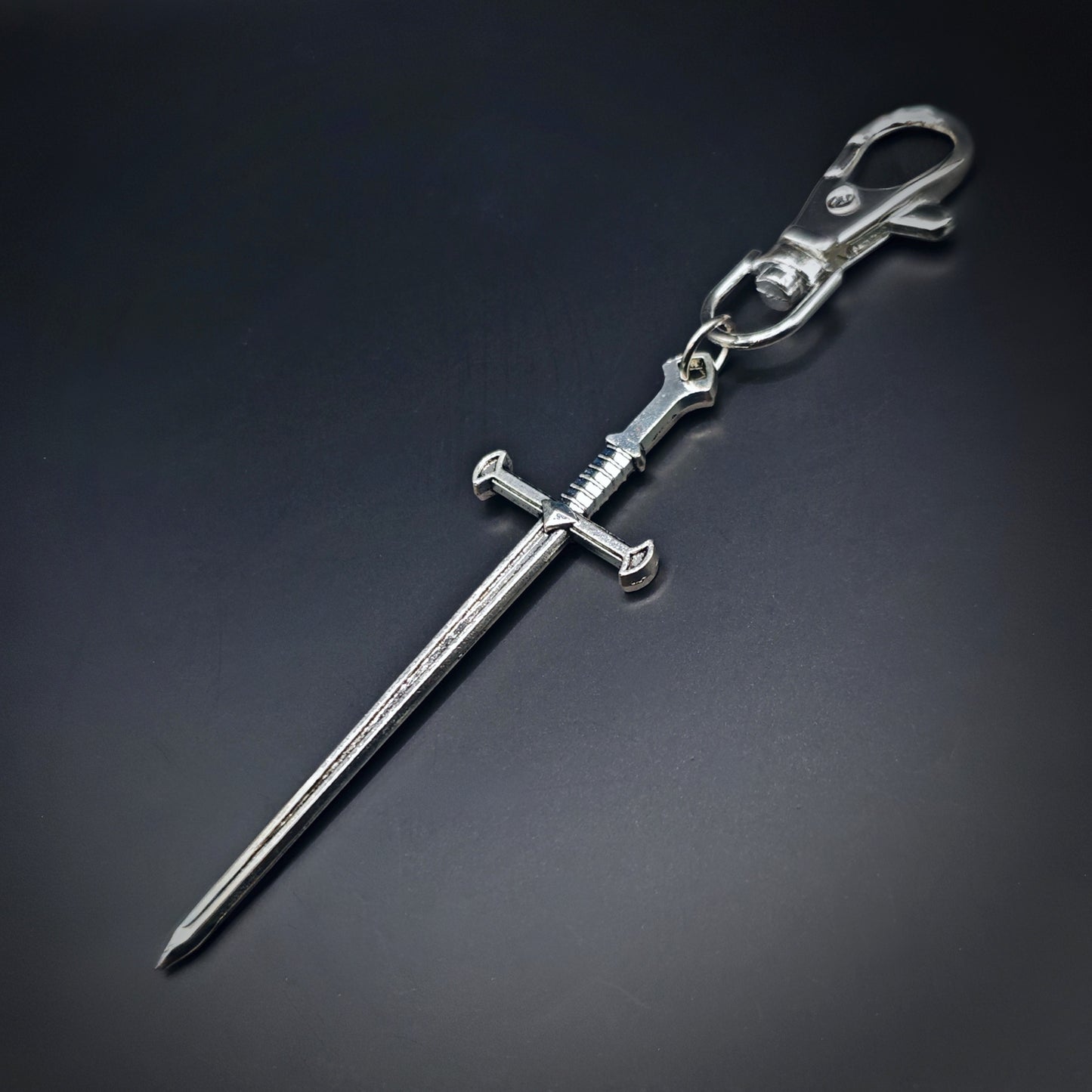 Silver sword keyring on a dark gray background