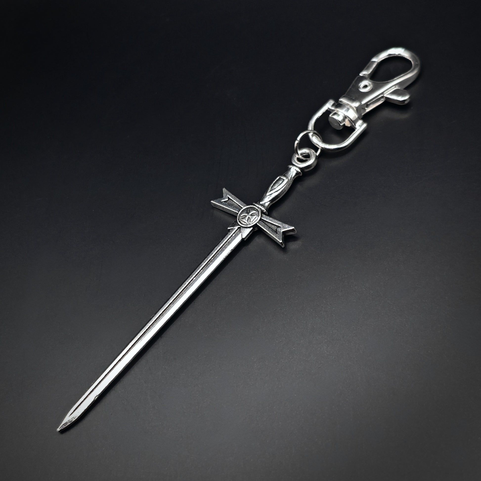Silver sword keyring with a cross design on a black background