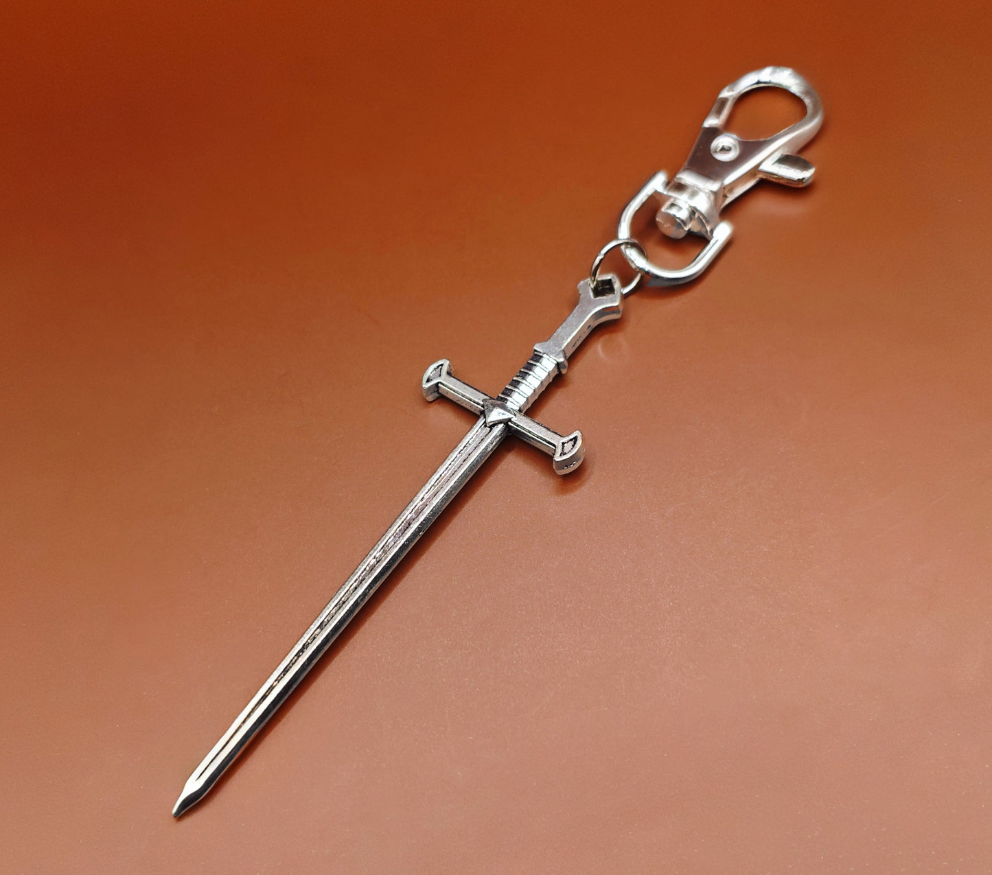Silver sword keychain on a brown background