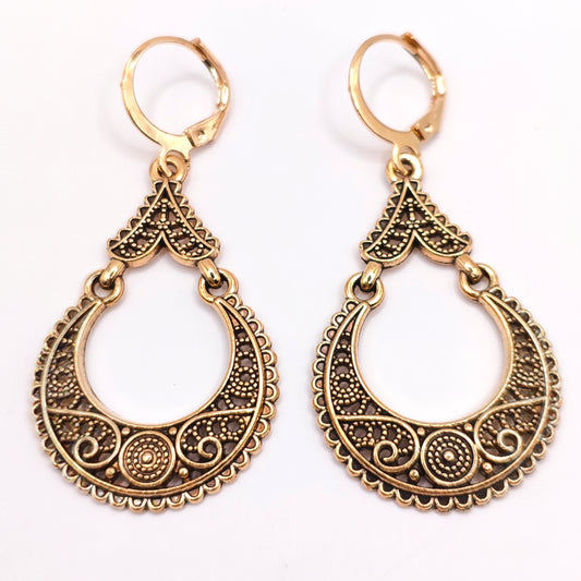 Pair of bohemian gold dangle hoop earrings with intricate filigree designs on a white background