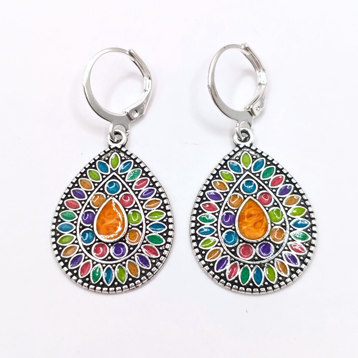 Little hippie dangle earrings with a colourful enamel mandala inlaid into silver, on a white background.