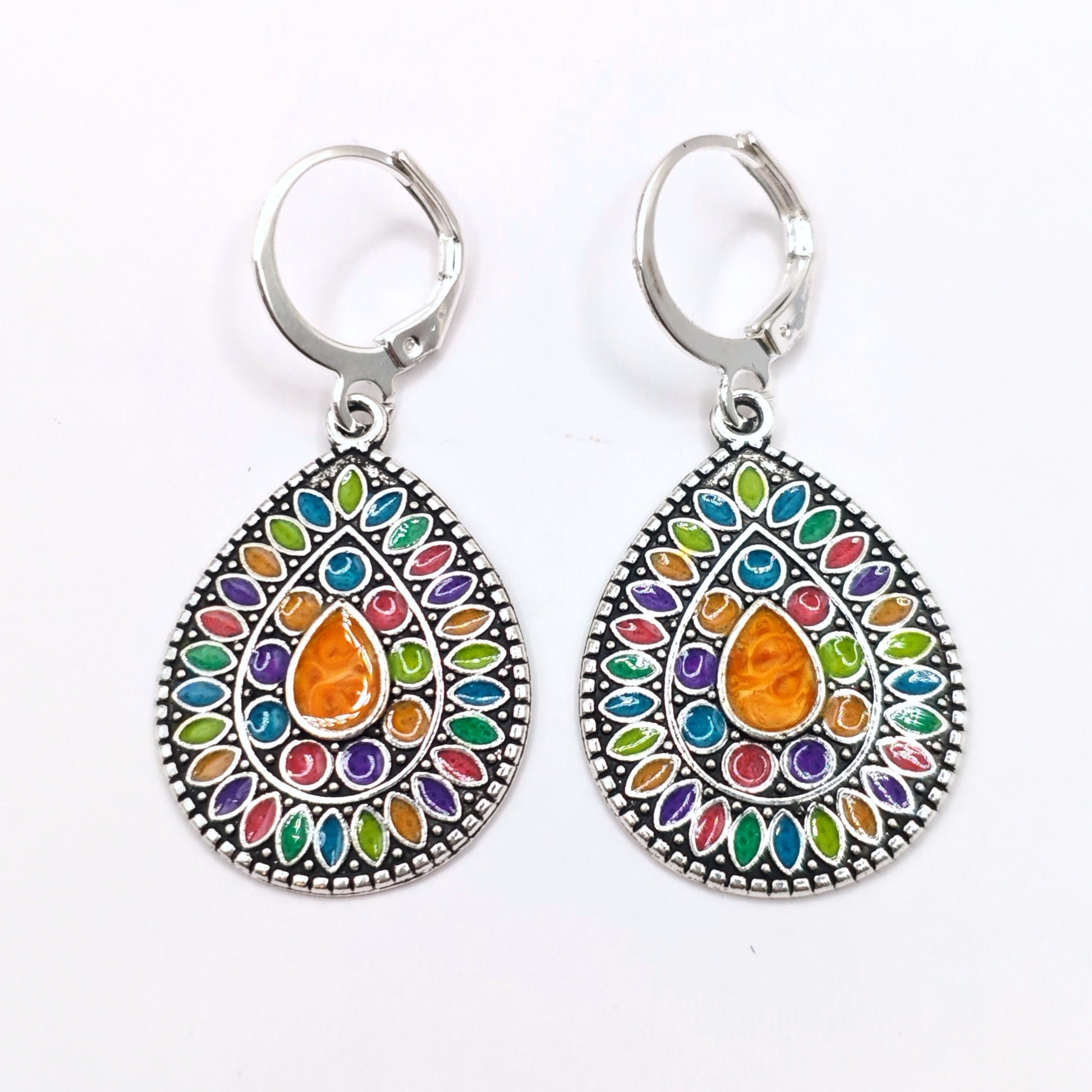 Little hippie dangle earrings with a colourful enamel mandala inlaid into silver, on a white background.