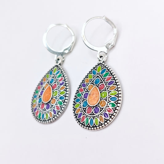 Side view of multicolored bohemian dangle earrings with silver hoops. 