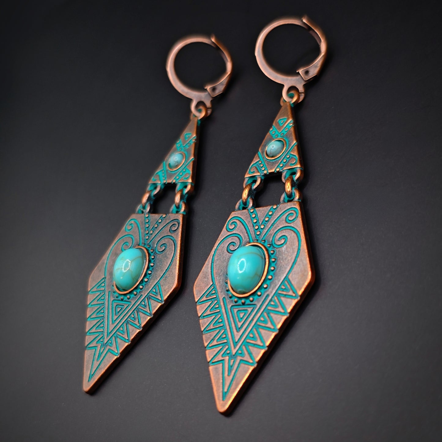 Pair of bohemian copper and turquoise dangle earrings on a dark background