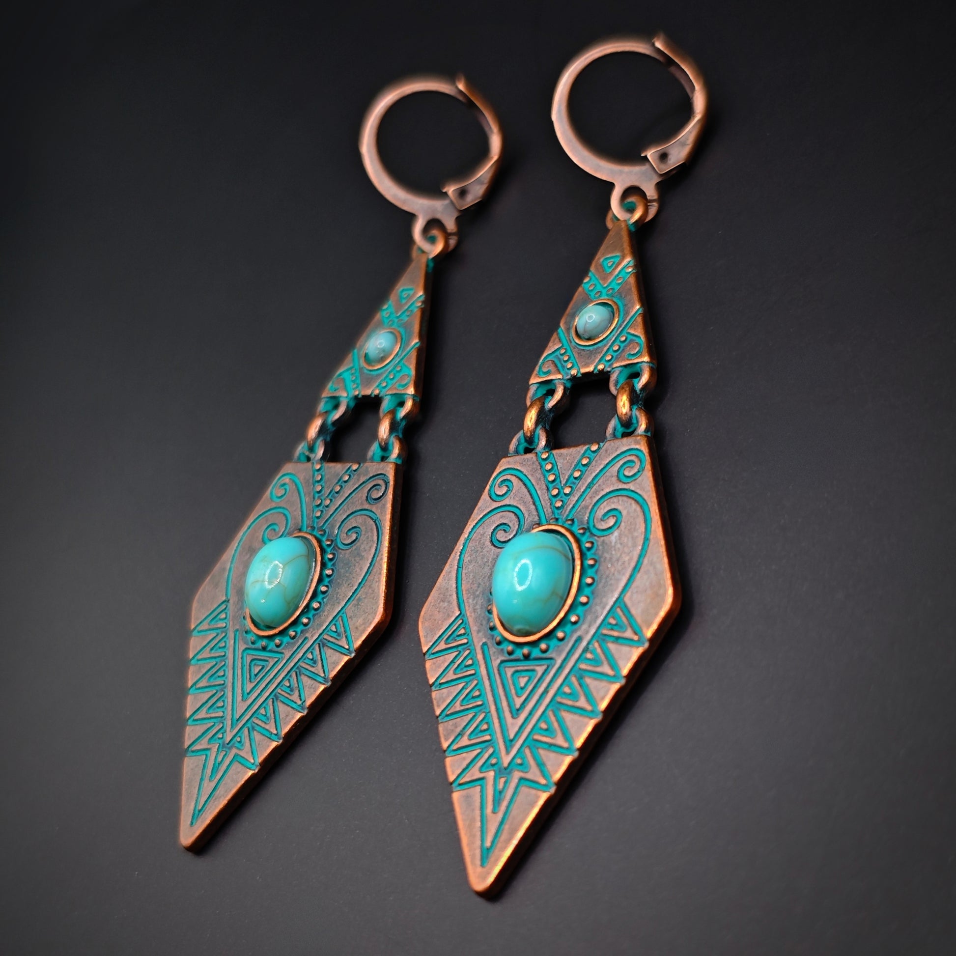 Pair of bohemian copper and turquoise dangle earrings on a dark background