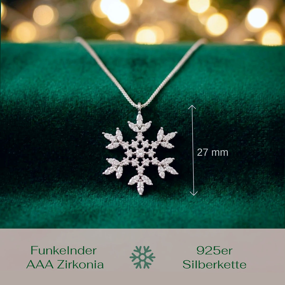 A silver snowflake pendant necklace with clear stones, displayed on a dark green velvet surface with a chain extending upward. A vertical measurement marker indicates the pendant height as 27 mm.