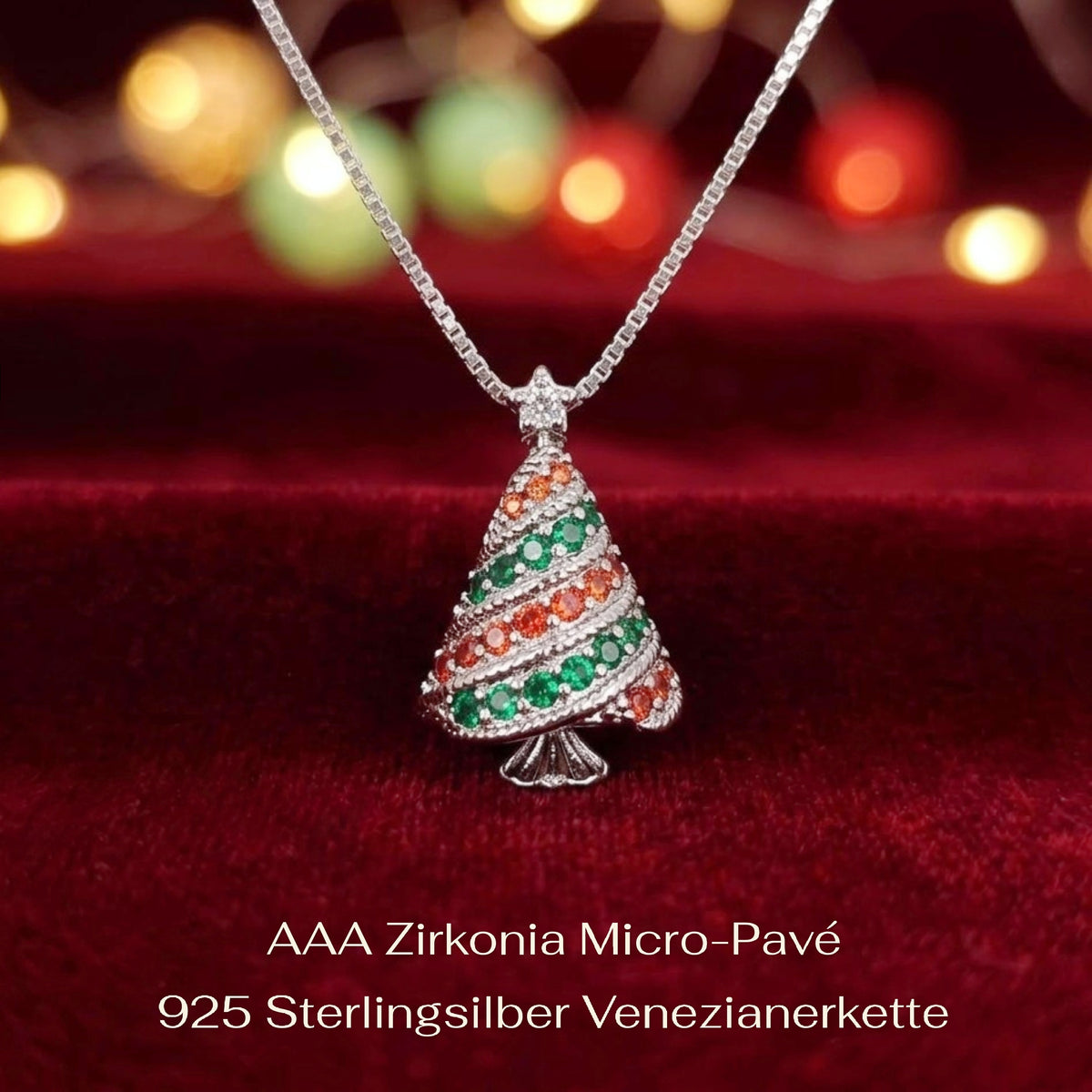 A 925 silver Christmas tree pendant necklace adorned with green and orange cubic zirconia crystals, resting on a deep red velvet surface with a warm bokeh background.