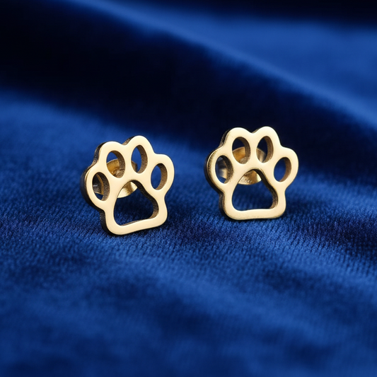 Gold paw print earrings on a blue fabric background