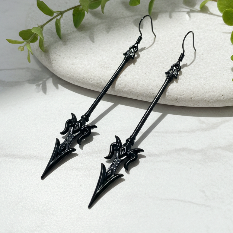 long black mace or axe earrings on a stone background in sunlight