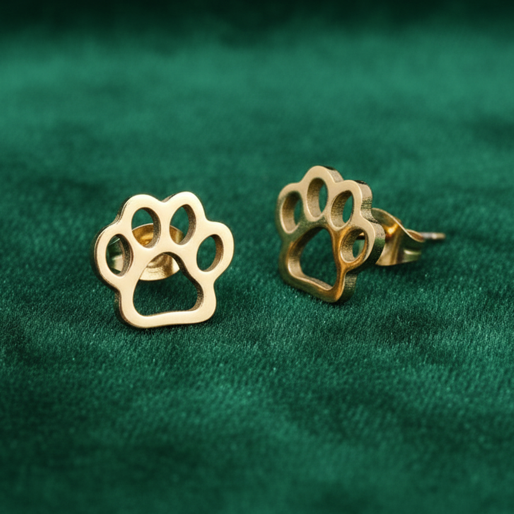 Gold paw print earrings on a green fabric background