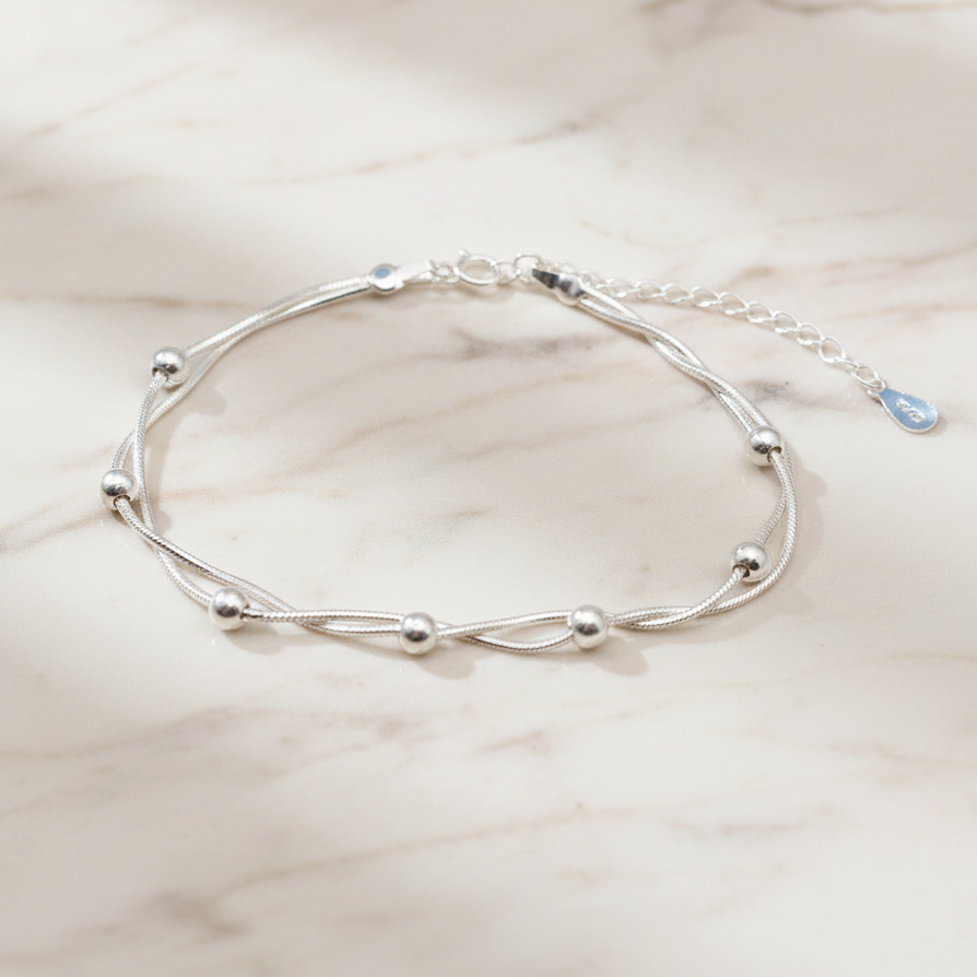 925 Silver Bracelet with two intertwined snake chains and round beads, on a marble background.