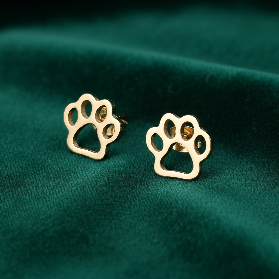 Gold paw print earrings on a green fabric background