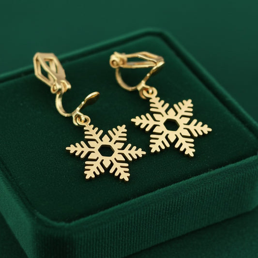 Gold snowflake earrings with clip ons  on a green velvet background