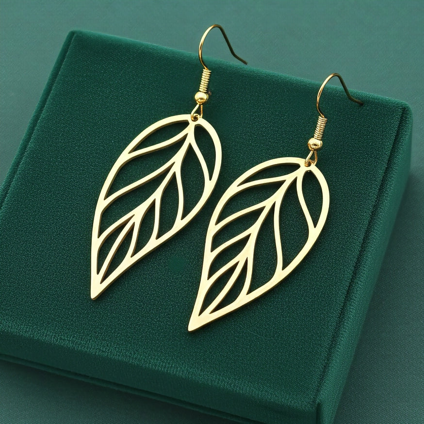 Large gold stainless steel leaf earrings with hooks on a green background