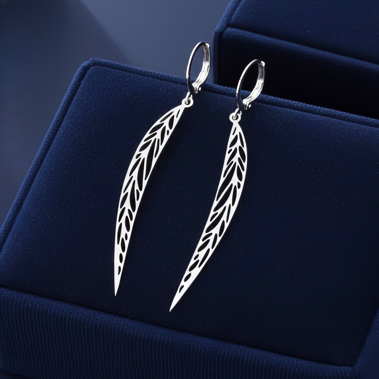 Long pointy stainless steel leaf earrings with silver hoops on a blue background
