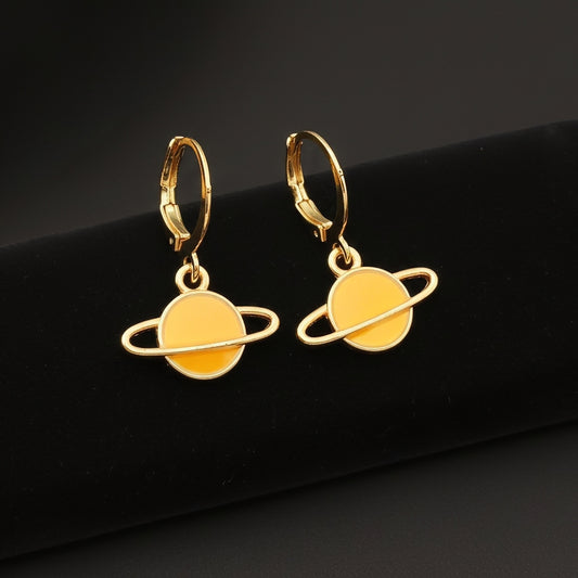Yellow Saturn planet earrings with gold hoops on a black background