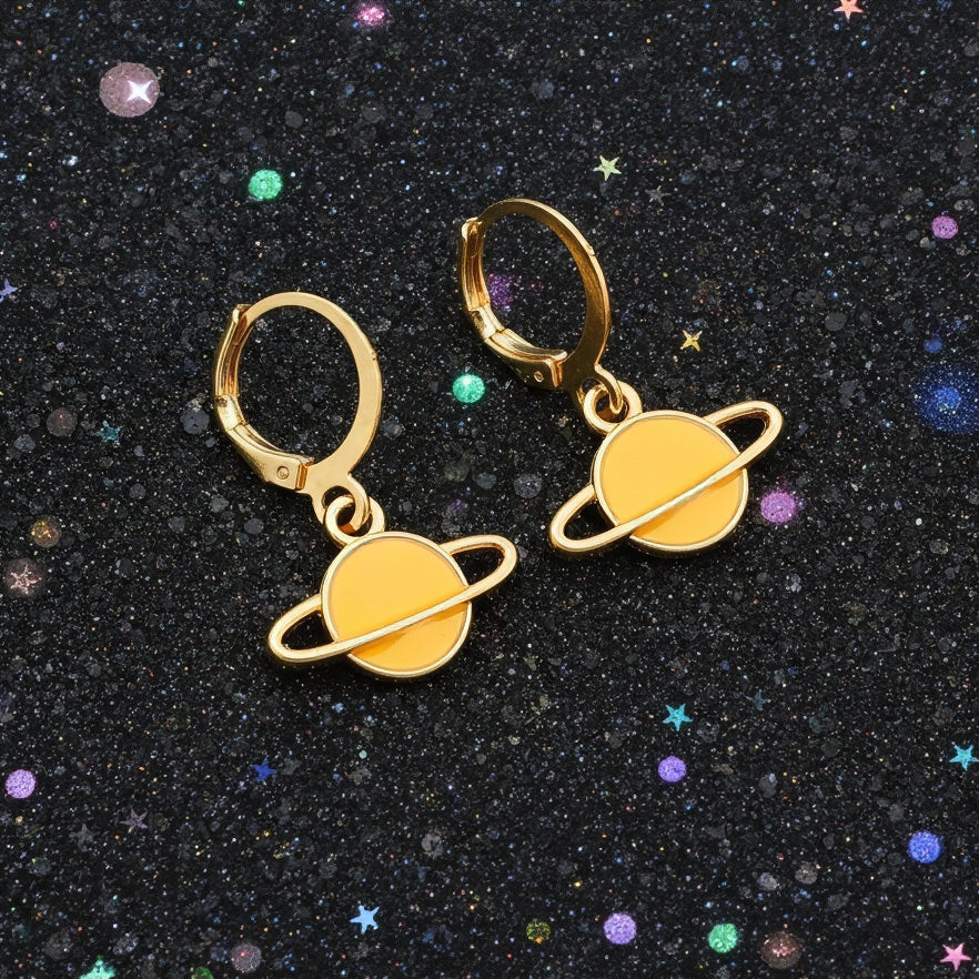 Yellow Saturn planet earrings with gold hoops on a starry background