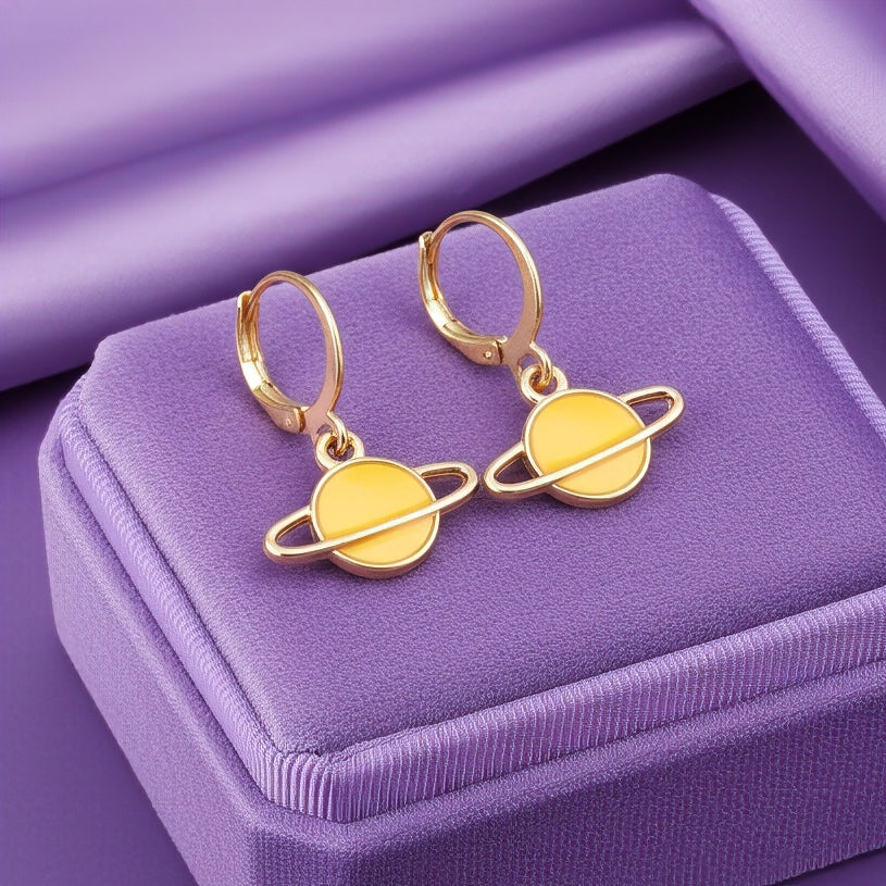 Yellow Saturn planet earrings with gold hoops on a purple background
