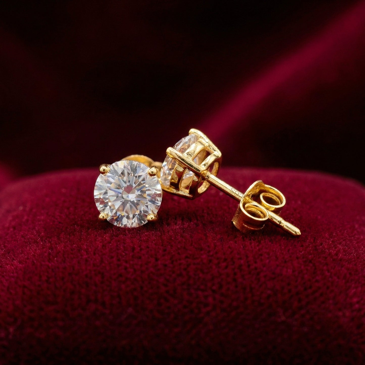 Sparkly gold 925 silver stud earrings with white cubic zirconia crystals on a red background