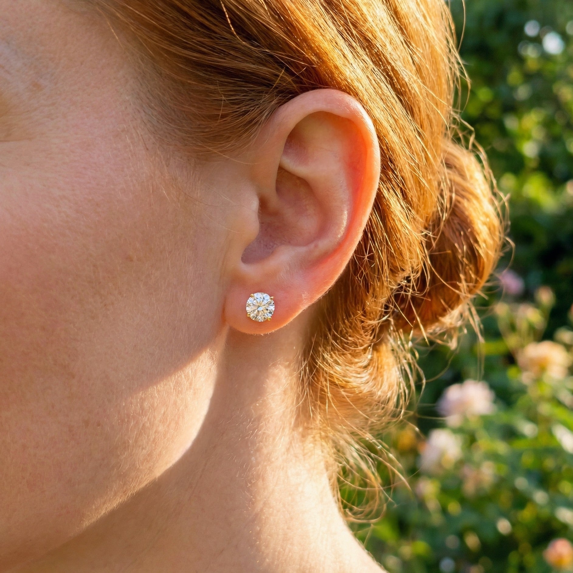 A woman with red hair wearing Sparkly gold 925 silver stud earrings with white cubic zirconia crystals outside in the sun