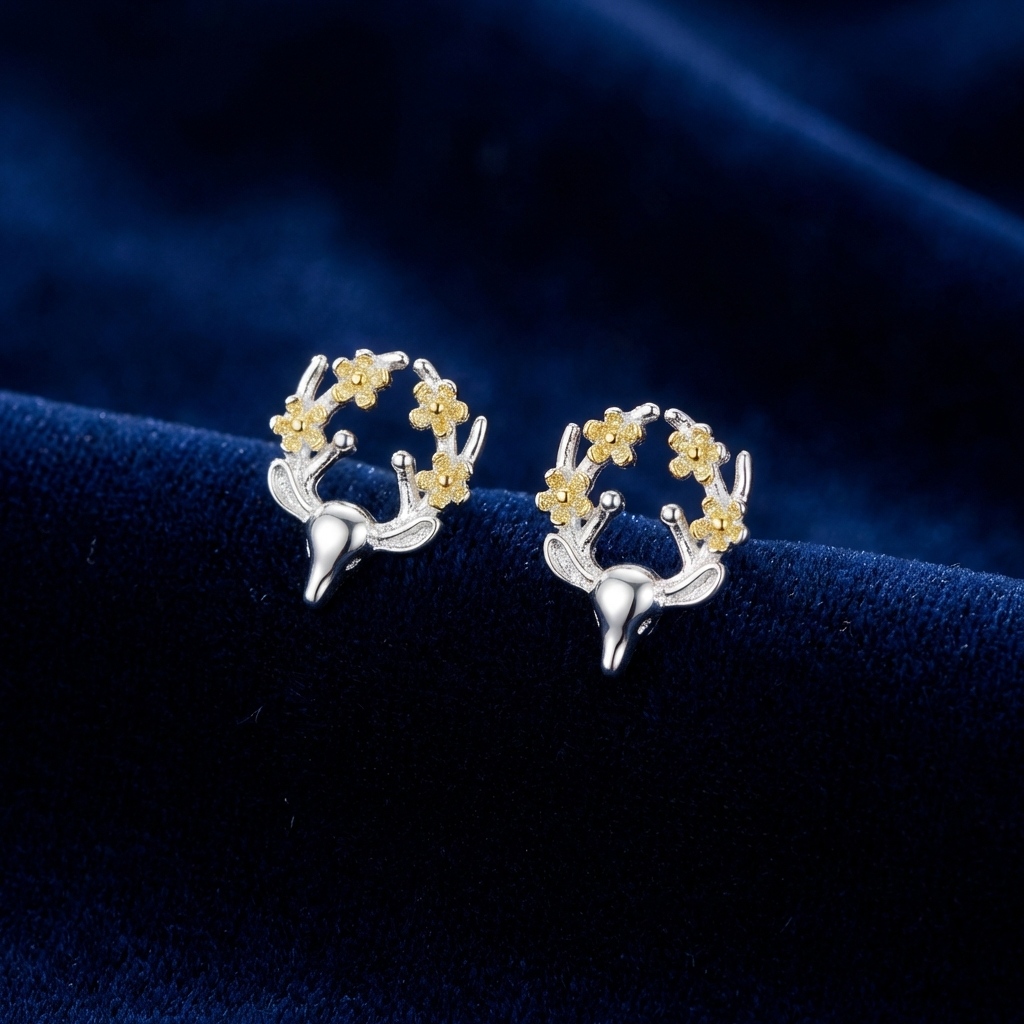 Silver and gold deer earrings with flowers on the antlers on a blue background