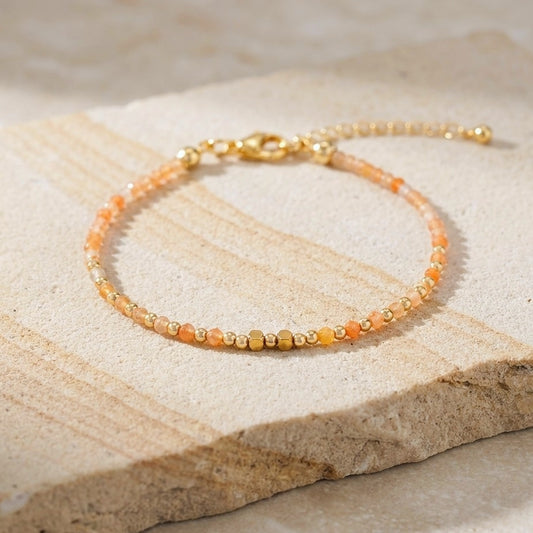 Yellow aventurine beaded boho bracelet with gold spacer beads and orange gemstone beads, on a light stone background