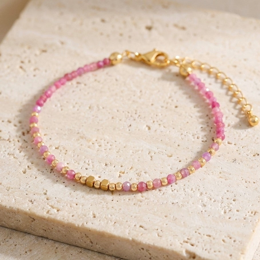 Boho beaded bracelet with natural pink strawberry quartz gemstone beads with natural inclusions and speckles, on a light stone background