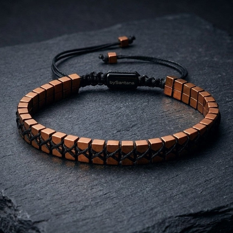 Men's hematite bracelet with copper cube beads woven together and an adjustable cord, on a dark background