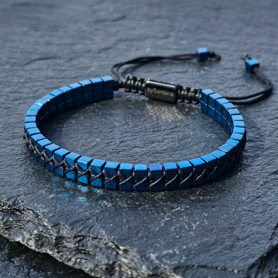 A men's metallic blue Hematite beaded bracelet with cube beads and adjustable cord on a stone