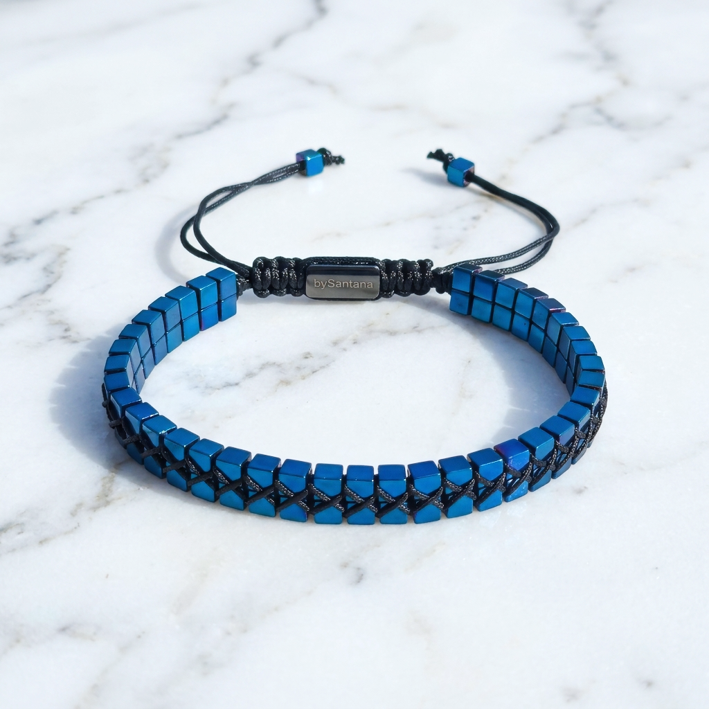 A men's metallic blue Hematite beaded bracelet with cube beads and adjustable cord on a marble surface