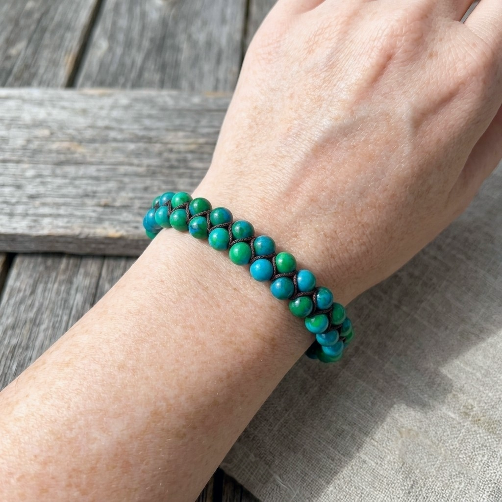A woman's wrist wearing a blue and green Chrysocolla bead bracelet 
