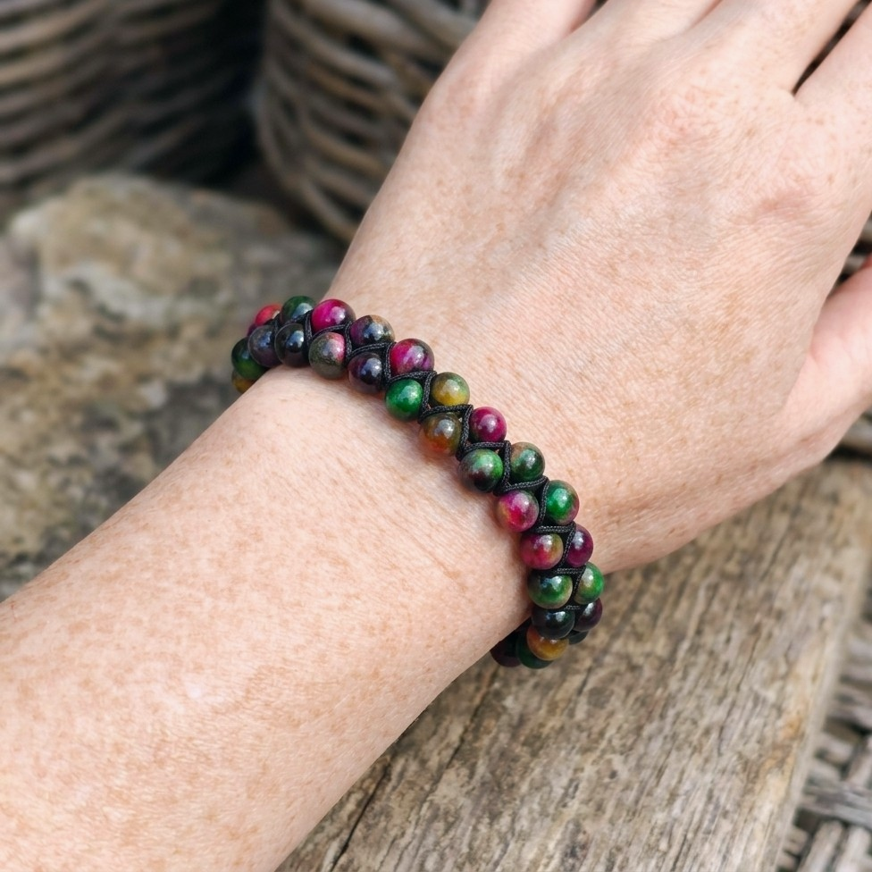 A woman's wrist wearing a colourful Tiger's Eye bracelet with a double row of pink, green and yellow gemstone beads
