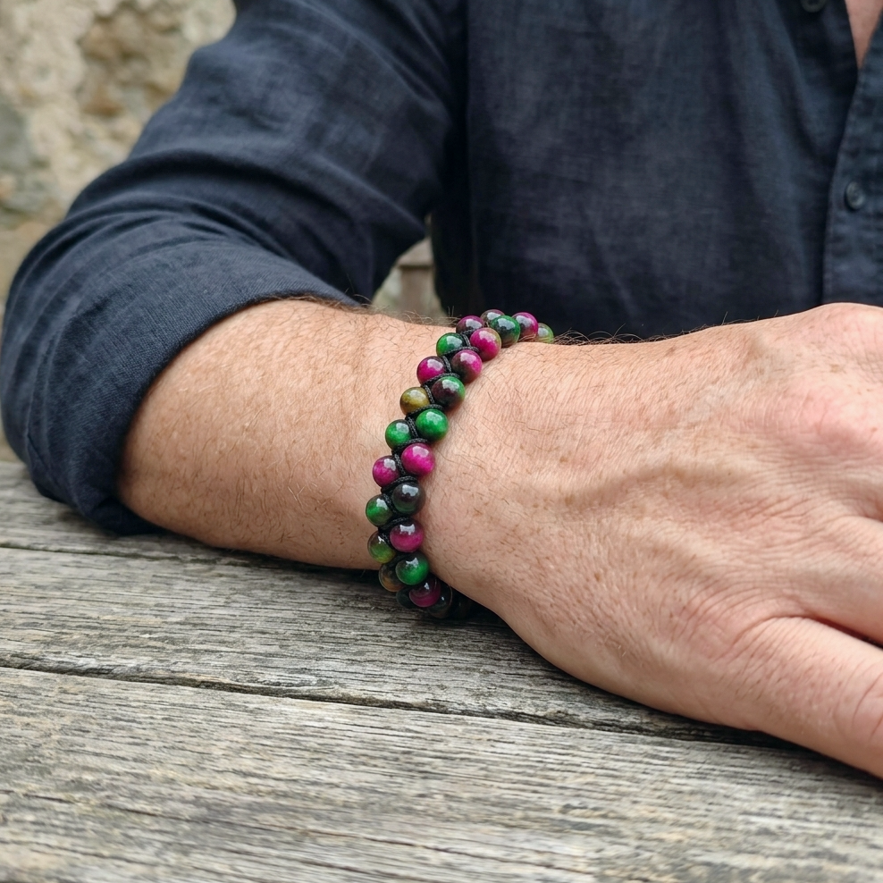 A man's wrist wearing a colourful Tiger's Eye bracelet with a double row of pink, green and yellow gemstone beads