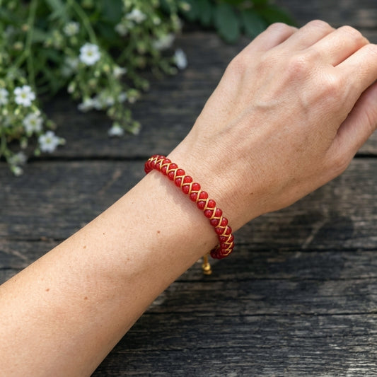 Red agate braided bracelet on a wrist with a natural wood background