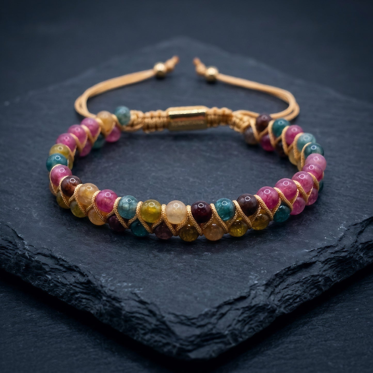 Multicolored Tourmaline beaded gemstone bracelet with beige cord wrapping on a dark background. the double row bracelet has pink, yellow, green and blue beads.