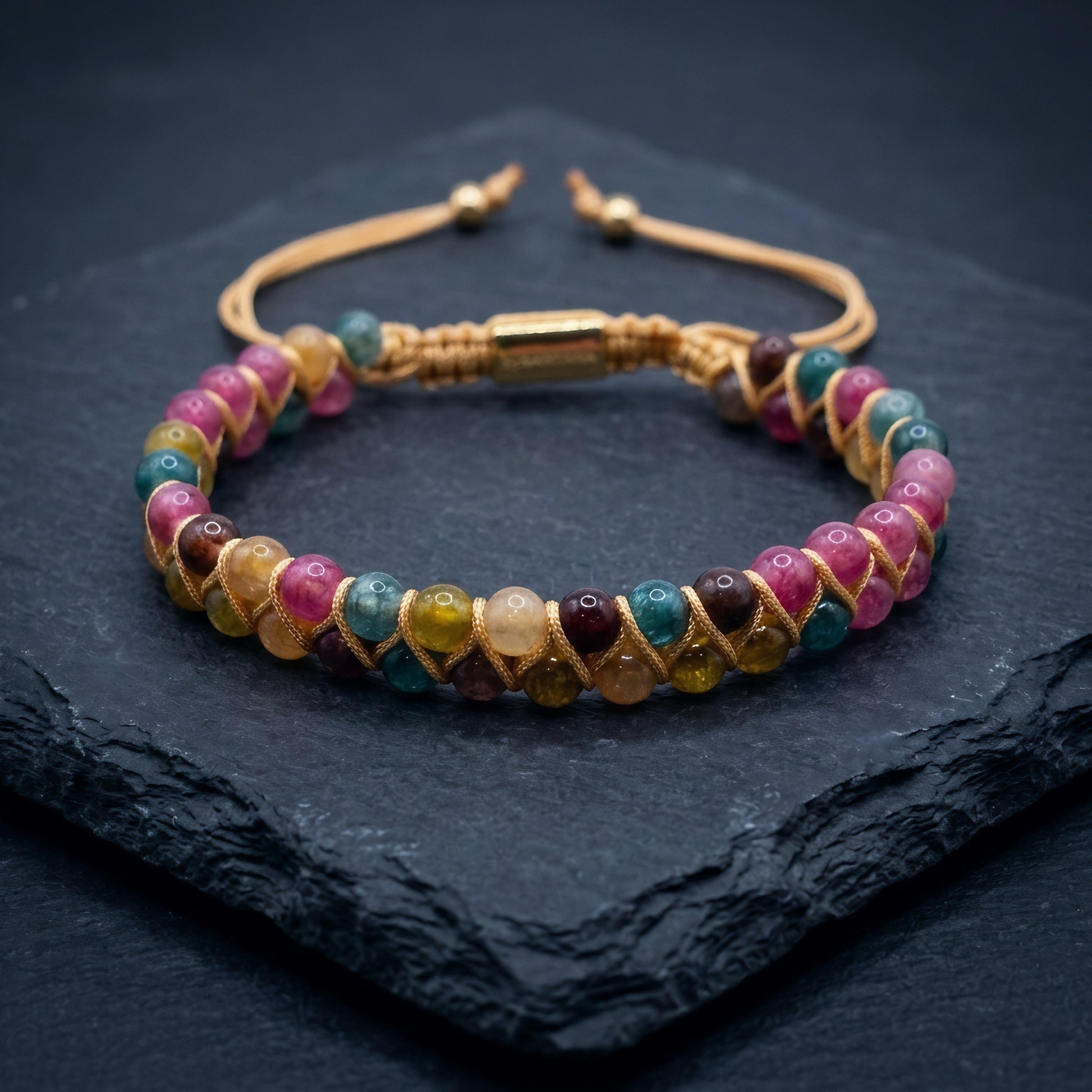 Multicolored Tourmaline beaded gemstone bracelet with beige cord wrapping on a dark background. the double row bracelet has pink, yellow, green and blue beads.