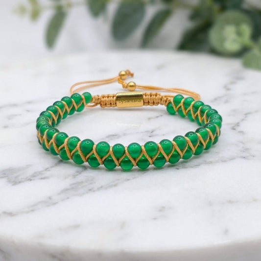 Green agate gemstone beaded bracelet, woven with a double row of natural stone beads, on a light stone surface with greenery behind