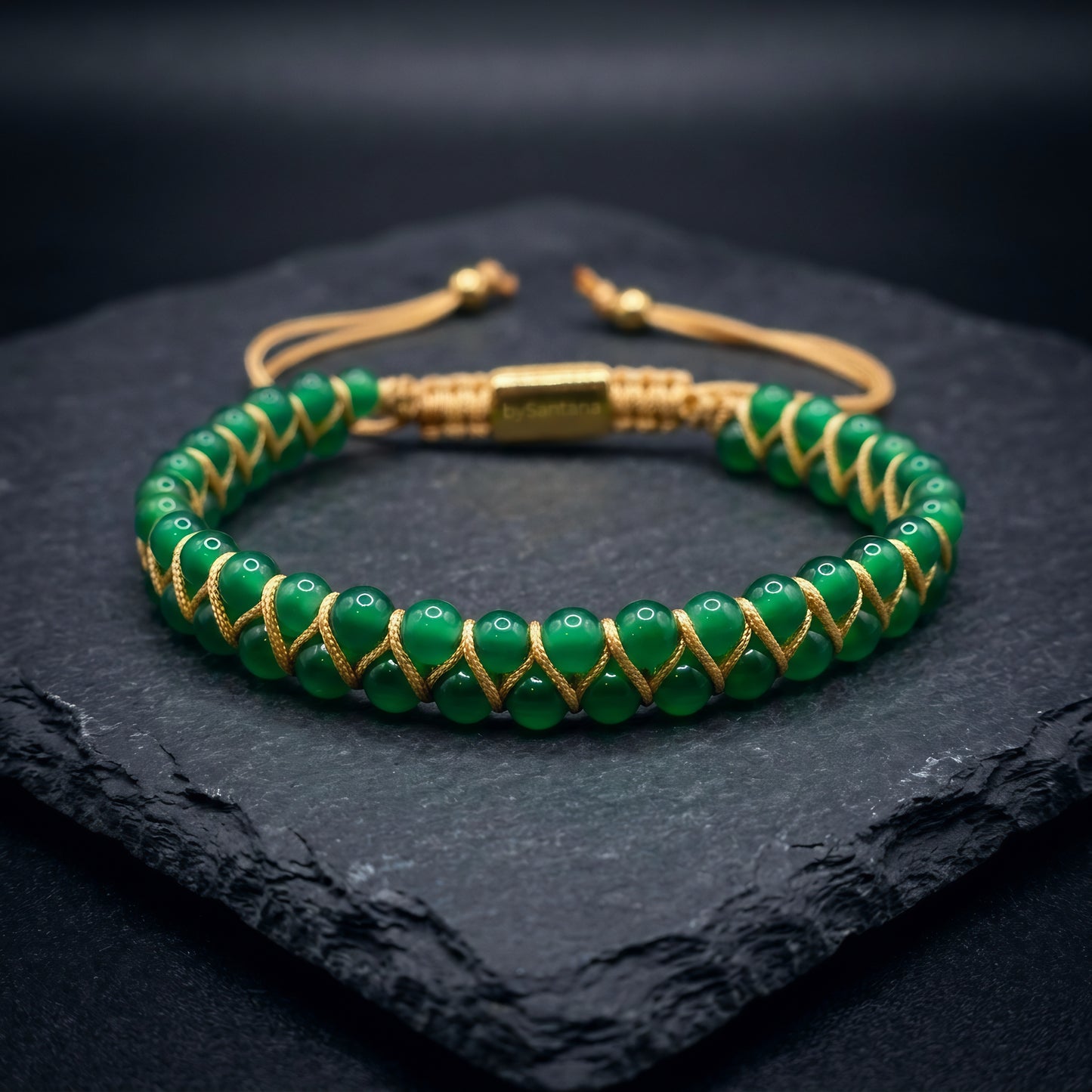 Green agate gemstone beaded bracelet, woven with a double row of natural stone beads, on a dark stone surface