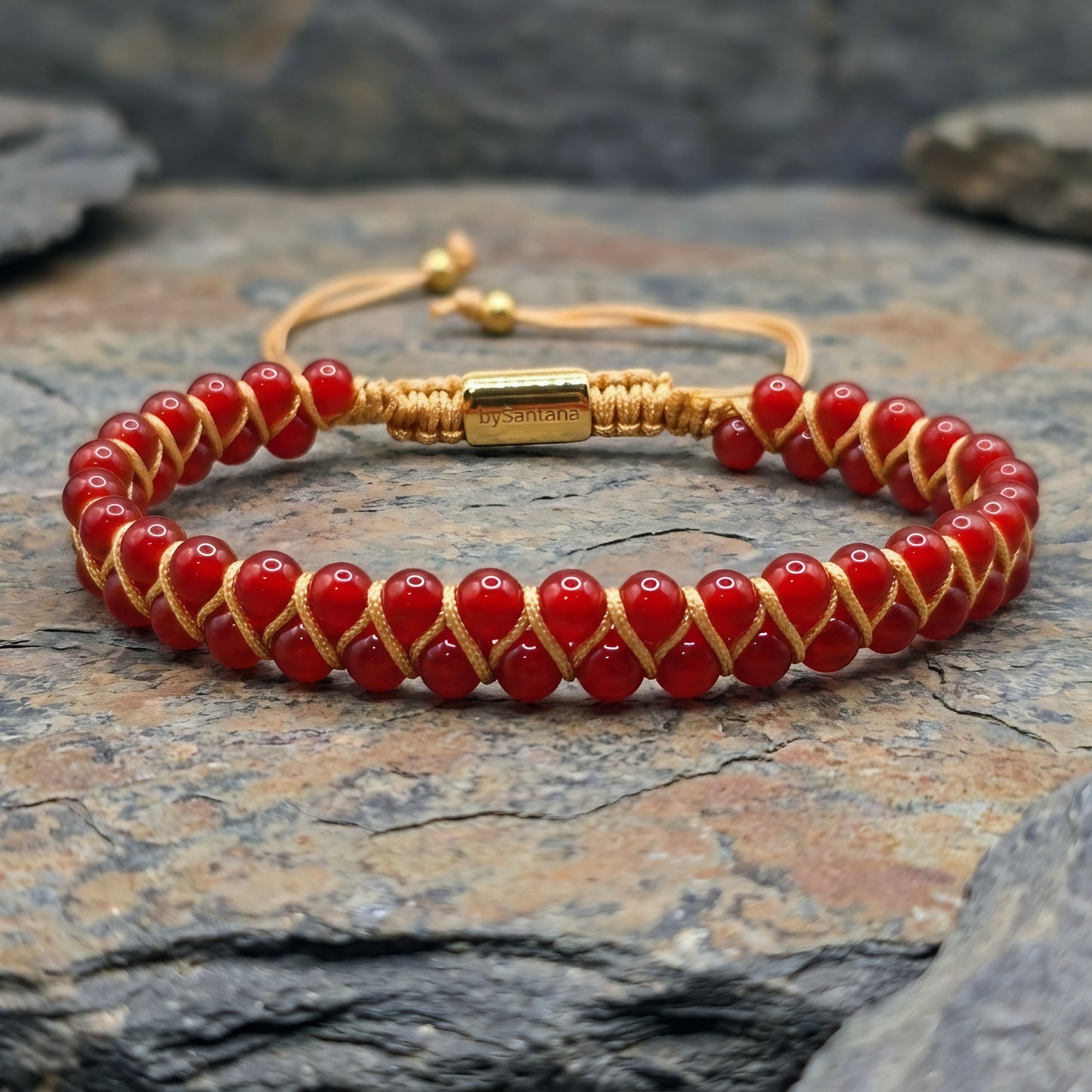 Bead bracelet with red agate gemstone beads in a double row, woven with an adjustable drawstring cord, on a stone surface 