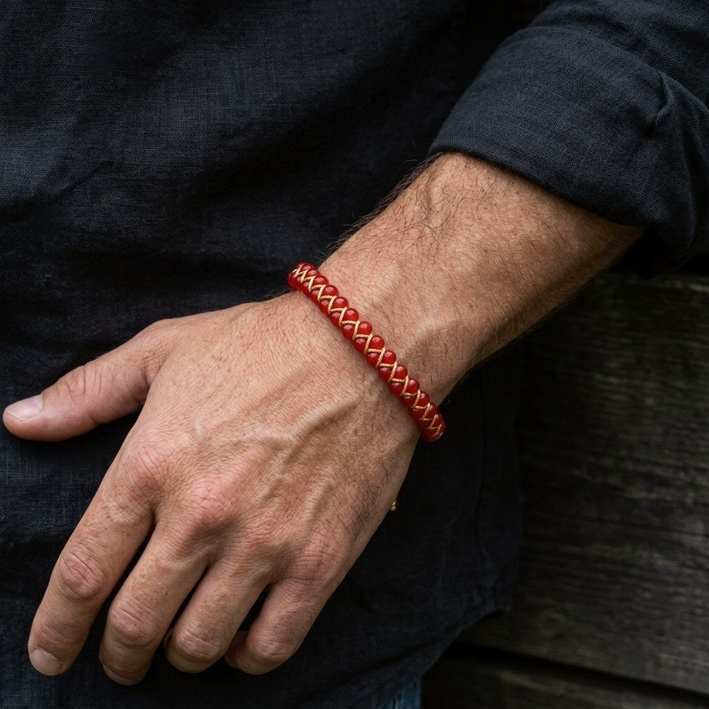 Red braided bracelet on a man's wrist with a dark background