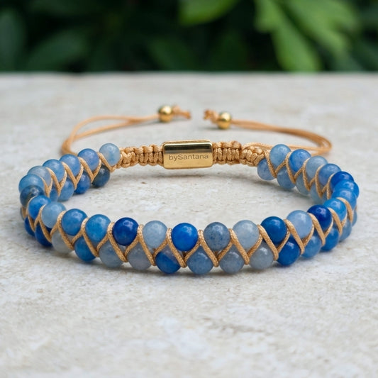 Blue aventurine beaded gemstone  bracelet with gold accents on a light stone surface with greenery in the background