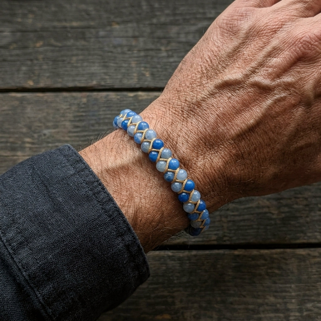 A man's hand wearing a blue beaded bracelet on a wooden surface